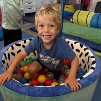 Smiling boy playing in a colorful ball pit
