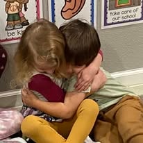 Two young children sharing a hug in the classroom