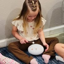 Young girl playing a small white chime instrument