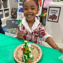 Smiling child with a decorated Christmas tree treat on a green table