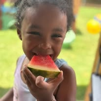 Smiling child eating a slice of watermelon outdoors