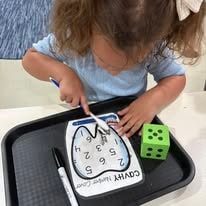 Child doing a counting activity with a dry-erase mat and dice