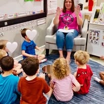 Teacher reading to children seated on a classroom rug