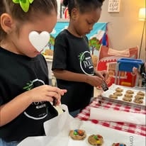 Two children in matching black shirts decorating cookies with frosting