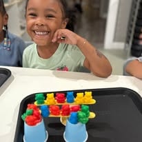 Smiling child playing with colorful counting bears and cups on a tray