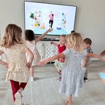 Children dancing together following an exercise video on TV