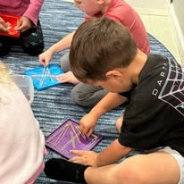 Young boy playing with a geometric peg and pattern board on a carpet