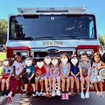 Children sitting on the bumper of a red Denton fire truck