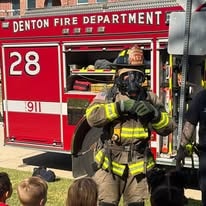 Denton firefighter in full gear in front of a fire truck