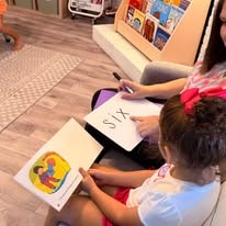 Teacher helping a young child learn letters with flashcards