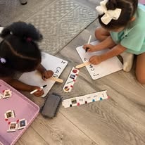 Two children matching letters and learning cards on a wooden floor