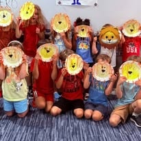 Group of children holding up paper-plate lion face crafts