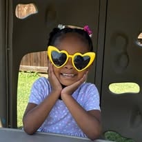 Smiling girl wearing yellow heart sunglasses playing outside at the playground