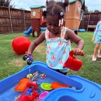 Child playing with toys at an outdoor water table