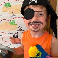 Child dressed as a pirate with eye patch and toy parrot