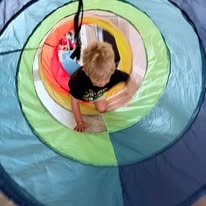Child crawling through a colorful pop-up play tunnel