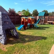 Backyard playground with climbing wall, playhouse slides, and swing set