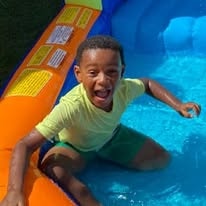 Laughing boy playing in an inflatable backyard pool