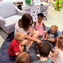 Teacher reading with a group of young children on a classroom rug