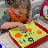 Young child doing a paint-stamping activity on yellow paper