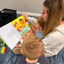 Teacher reading a colorful children's book to a toddler