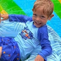 Smiling child in swimwear on an inflatable ring in a colorful water play area